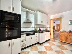 a large kitchen with white cabinets and black appliances at Casa De Noor in Órgiva