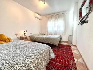 a bedroom with two beds and a red rug at Casa De Noor in Órgiva