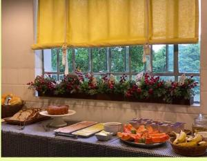 una mesa con comida en ella con una ventana en Pousada da Alê, en Blumenau