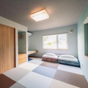 two beds in a room with a checkered floor at The Box House in Furano