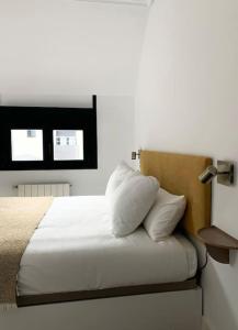 a bedroom with a bed with white sheets and pillows at Atico con espléndida terraza in Comillas