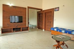 a living room with a couch and a flat screen tv at Chimneys Homestay - Full House, Near to Falls & Trek in Sakleshpur