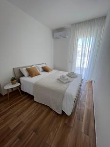a white bedroom with a bed and a wooden floor at Welcome Home Quartu Sant'Elena in Quartu SantʼElena