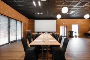 a conference room with a table and chairs and a white screen at Plaża Resort in Bogaczewo