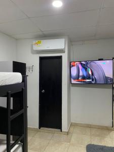 um quarto com uma porta preta e uma televisão na parede em Mami Yola em Valledupar