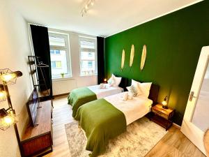 - une chambre avec 2 lits et un mur vert dans l'établissement Das Berg Apartment Rüttenscheid, Netflix, nahe Messe, Klinikum, à Essen
