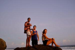 um grupo de pessoas em pé sobre rochas na praia em The Lost Hostels, Weligama Beach - Sri Lanka em Weligama