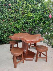 a wooden picnic table and stool next to a bush at Casa Aeroporto Maceió in Maceió