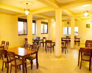 a dining room with tables and chairs and windows at Ubuntu Palace Hotel in Kampala
