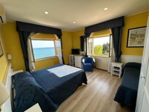 a bedroom with a bed and two windows and the ocean at Hotel L'Isola in Santa Marinella