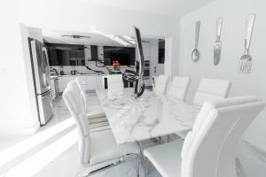 TamiamiにあるSpacious Miami Home Heated Pool BBQ L35の白いダイニングルーム(大理石のテーブル、白い椅子付)