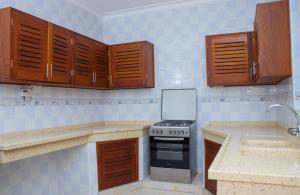 cocina con armarios de madera y fogones con ordenador portátil en 5 Bedroom Villa Near Pride Inn, en Mombasa