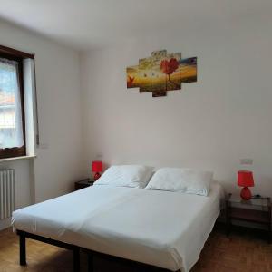 Un dormitorio con una cama blanca y una pintura en la pared en IL PAITITI, en Arco