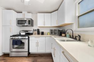 a white kitchen with a stove and a sink at Cozy 1bdr/1br home near downtown in Sacramento