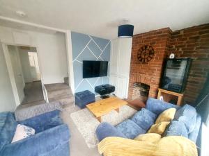 a living room with a blue couch and a tv at Woodside House - 4 Bed Town House - Central Reading - Free Parking in Reading