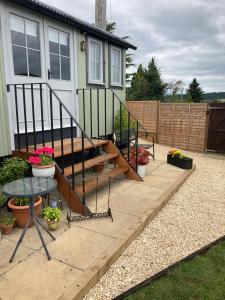 a patio with a table and some potted plants and a house at Cotswold shepherd hut with hot tub and sauna Dog friendly in Charlton
