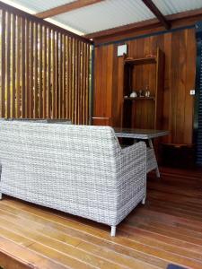 a wicker couch sitting on a wooden floor with a table at Bungalow de charme in Montjoly