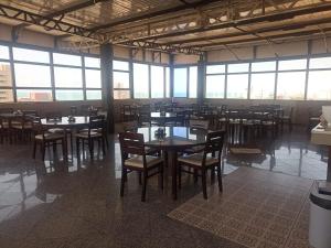 a dining room with tables and chairs and windows at Boreas Apart Hotel in Fortaleza