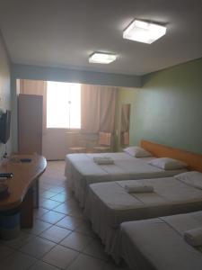 a hotel room with three beds and a window at Boreas Apart Hotel in Fortaleza