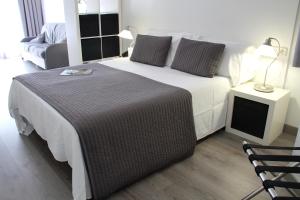 1 dormitorio con 1 cama blanca grande y 1 silla en Aparthotel Atenea Calabria, en Barcelona