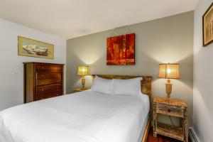 um quarto com uma cama branca e 2 candeeiros em Woodbridge Condo by Snowmass Vacations em Snowmass Village