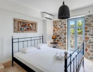 a bed in a bedroom with a brick wall at Aqua Blu Syros 1,3 in Posidhonía