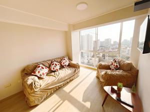 sala de estar con 2 sofás de cuero y ventana grande en Habitación privada con hermosa vista de Barranco, en Lima