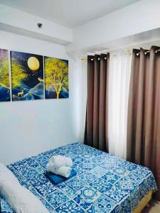 a bedroom with a bed with two paintings on the wall at NJ's Place, Shore 1 Residences, MOA Complex, Pasay City, Philippines in Manila
