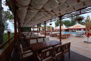 ein Restaurant mit Holztischen und -stühlen und einem Pool in der Unterkunft Hotel Central in Mamaia