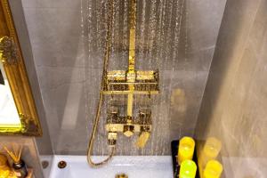 a bath tub with a shower with a gold chain at Lady Suite in Cluj-Napoca