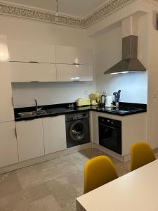 a kitchen with white cabinets and a washer and dryer at Les magnifiques jardins d’Assilah in Asilah