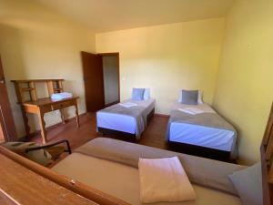 um pequeno quarto com duas camas e uma mesa em Casa dos Coqueiros - Cama, Café e Eventos em Itabirito
