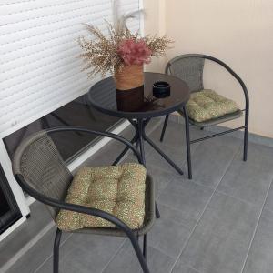 a table with two chairs and a vase with flowers on it at Apartman Prodan in Sombor