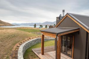 a house with a solar roof and a stone wall at Alpine Lodges in Lake Tekapo