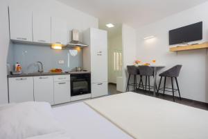a kitchen with white cabinets and a sink and a table at Studio apartman Maris in Kastel Stari