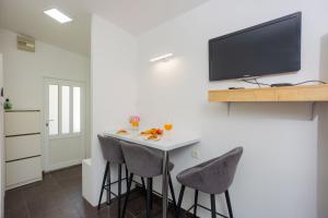 a kitchen with a bar with stools and a tv on a wall at Studio apartman Maris in Kastel Stari