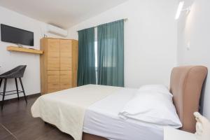 a bedroom with a white bed and a television at Studio apartman Maris in Kastel Stari