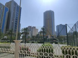 a white fence in front of a city with tall buildings at Live Like A Family Home Away From Home in Sharjah