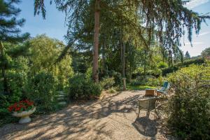 un giardino con tavolo, sedia e alberi di B&B Nouveauté a Vaals
