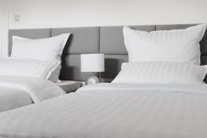 2 camas con sábanas blancas y una lámpara en un dormitorio en Wunderschöne, großzügige Wohnung, en Bad Soden am Taunus