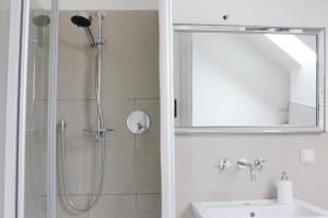 uma casa de banho com um chuveiro, um lavatório e um espelho. em Wunderschöne, großzügige Wohnung em Bad Soden am Taunus