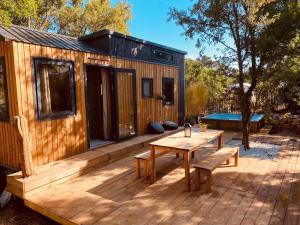 a cabin with a wooden deck with a table and benches at Tiny LiLouMaCa Cœur Ste Baume in Plan dʼAups