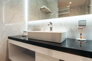 a bathroom with a white sink and a black counter at Elements Hotel & Shops Curaçao in Willemstad