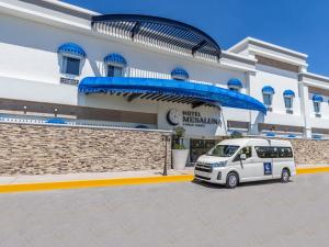 una furgoneta blanca estacionada frente a un edificio en Hotel Mesaluna Short & Long Stay en Ciudad Juárez