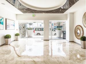 a lobby with a marble floor and potted plants at Hotel Mesaluna Short & Long Stay in Ciudad Juárez