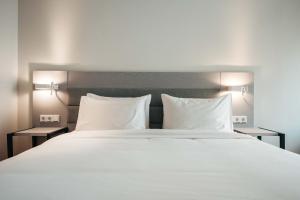 a large bed with white sheets and pillows at Elements Hotel & Shops Curaçao in Willemstad