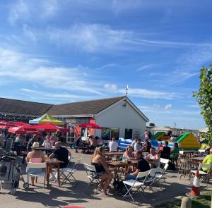 a group of people sitting at tables in front of a building at Golden Sands 6 Berth Beach front Ingoldmells beds made up for arrival WIFI in Ingoldmells