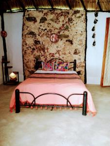 Cama en habitación con pared de piedra en Casa Maya 3 Culturas - Alberca - Wifi Starlink - Tour Sostenibilidad, en Izamal