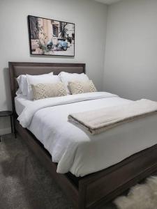 a large bed with white sheets and pillows on it at Serene Haven - 1 bedroom apartment. in Calgary