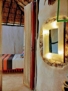 een spiegel aan een muur in een kamer met een bed bij Casa Maya 3 Culturas - Alberca - Wifi Starlink - Tour Sostenibilidad in Izamal